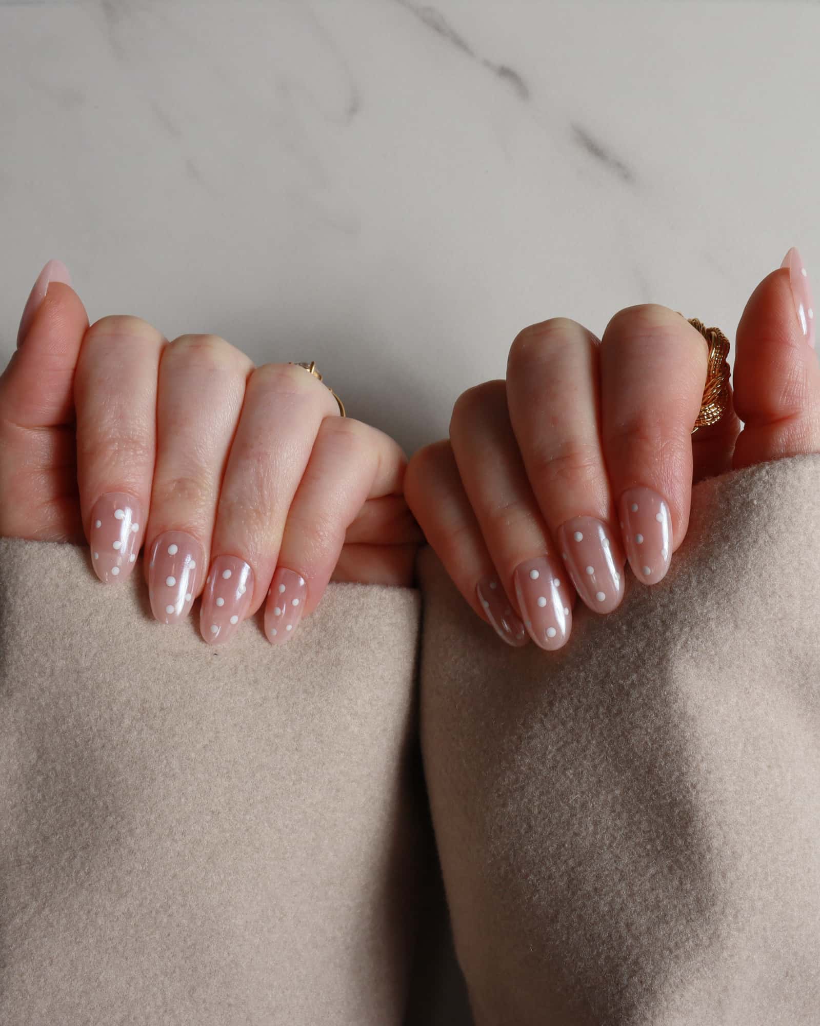 Close-up of hands with polished nails against a neutral background