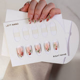 Nail art design sheet with floral patterns held by a hand