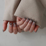 Close-up of hands with stylish nail designs wearing a beige coat.