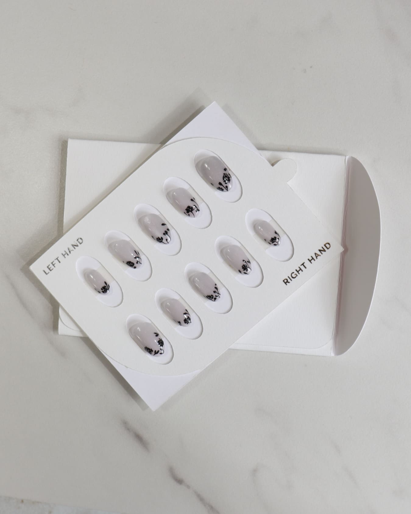 Set of false nails in a packaging box on a light gray background